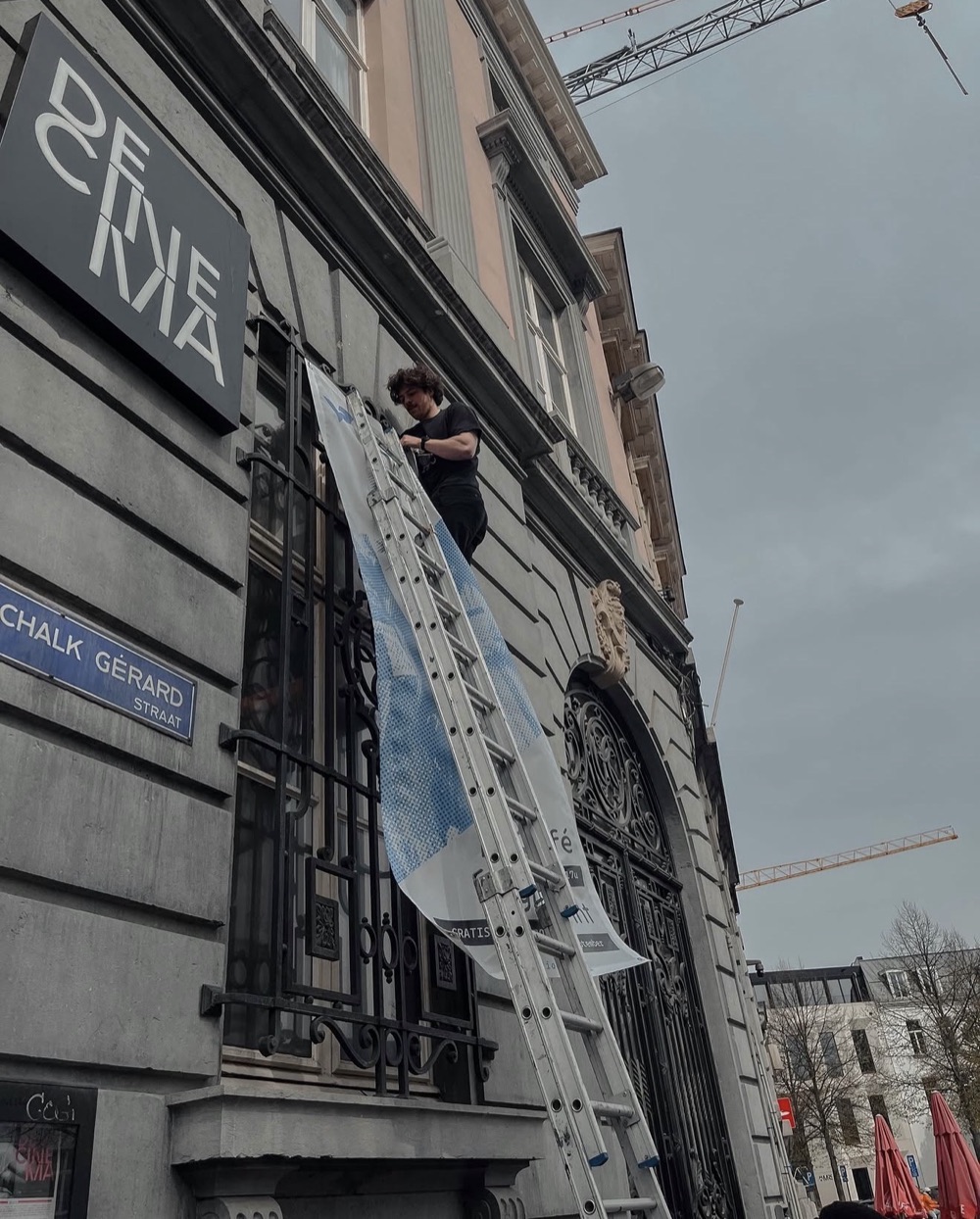 Arno Zaman hangt een spandoek aan een gevel in Antwerpen